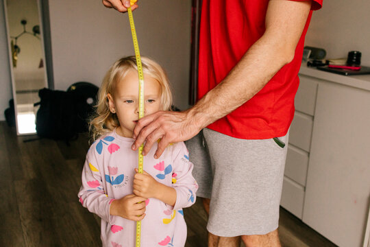 Father measuring daughter's height in cozy home setting