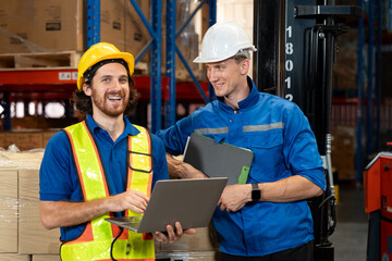 Warehouse workers sharing a light moment while discussing tasks using a laptop. This scene highlights effective teamwork, digital workflow, and a positive, collaborative workplace environment.