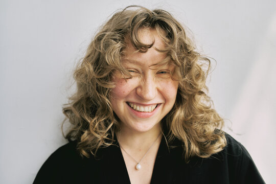 Smiling woman with curly hair enjoys cheerful moment indoors