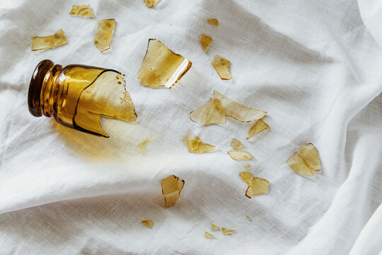 Glass Jar Shattered on White Fabric Creating a Scattered Mess