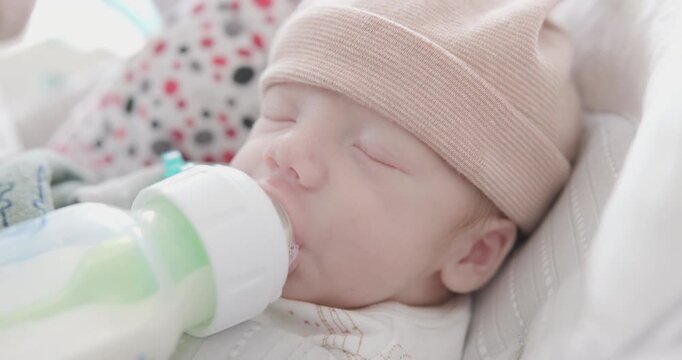 New Born Small Baby Drinking Bottle While Father Places Hand on Head