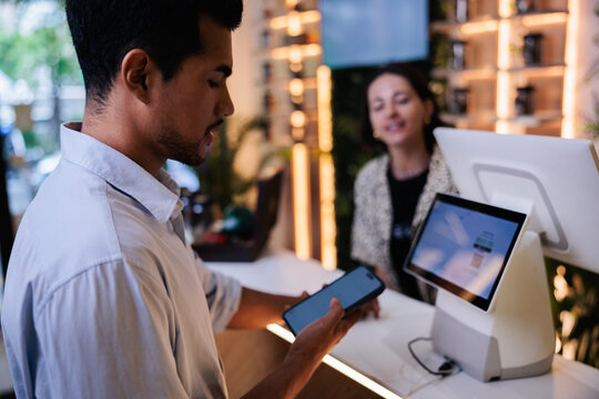 Man paying with phone at modern store checkout.