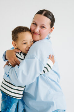 Mom and son share a warm hug in a bright studio setting