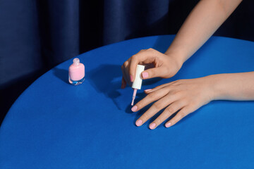 Woman applying pink nail polish, focusing on the hand