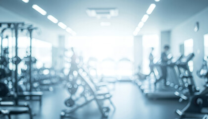 Blurred gym interior featuring modern exercise equipment and people actively working out, creating a vibrant and energetic fitness atmosphere.