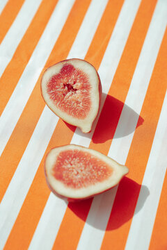 Fresh fig halves resting on a vibrant striped fabric