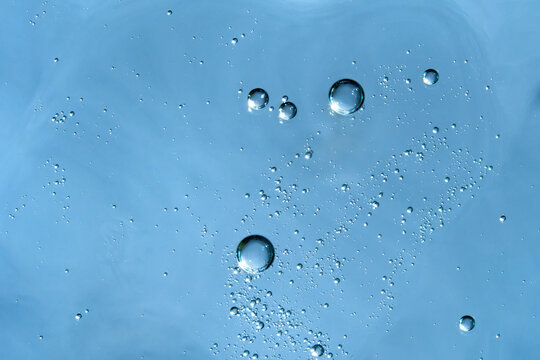Abstract textured background with bubbles in blue face serum. 