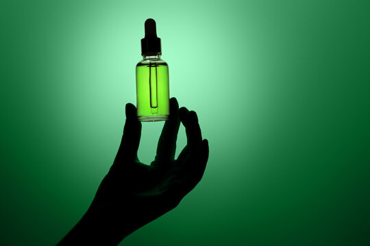 Hand holding dropper bottle with anti aging face serum.