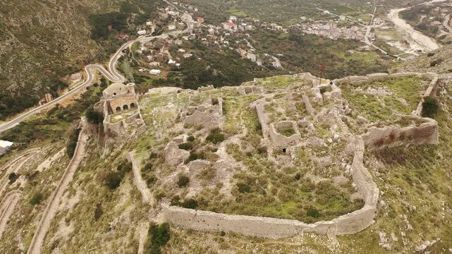 View from drone of ruined medieval Sopot Castle on hill above village of Borsh overlooking Ottoman-era Haji Bedo Mosque on spring day, Albania