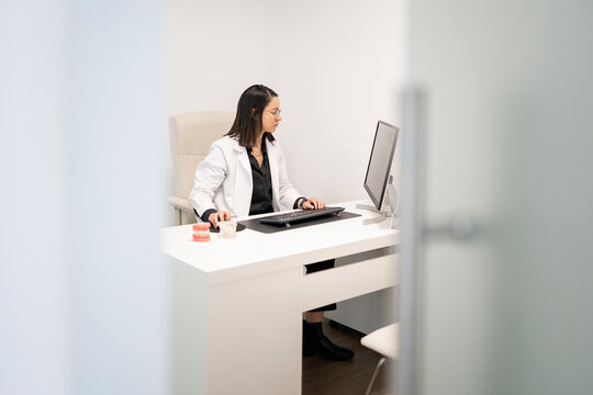 Dentist working on computer with dentures model in office