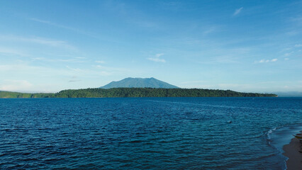 Fototapeta premium Aerial shot of serene island and dramatic volcanic mountain skyline.