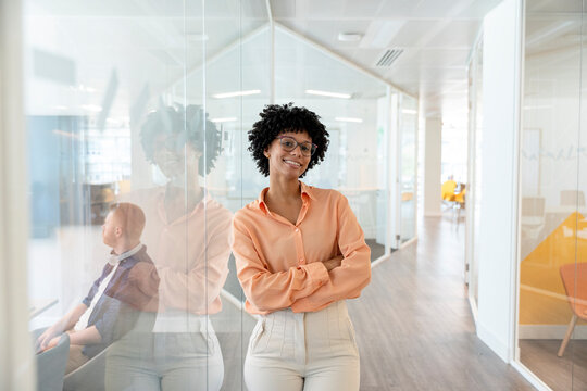 Confident businesswoman smiling with folded arms in modern office