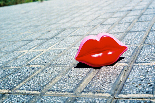 red lips on the sidewalk in harsh sunlight outdoors, 35mm