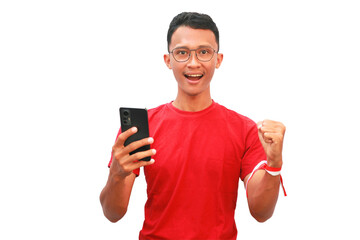 An Asian man wearing a red shirt and a red and white ribbon in his hand holding a cellphone with a happy expression