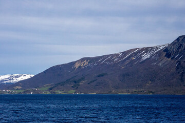Scenic Lofoten fjords, snowy mountains, green fields and coastal landscapes in spring. Stunning spring views of Lofoten Islands, Norway – snowy mountains, sparkling fjords, green fields.