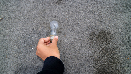 businessman holding a light bulb on sand 