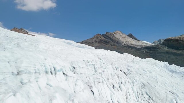 A thrilling, low-altitude aerial drone shot flies closely over the heavily crevassed and textured ice surface of the massive Pastoruri Glacier in the Peruvian Andes.