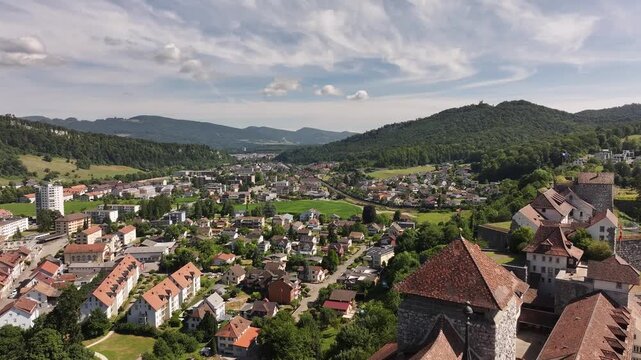 Expansive aerial view of Aarburg town, castle, and lush hills in the canton of Solothurn, Switzerland, with the Aare River winding through a charming mix of historic and modern architecture.
