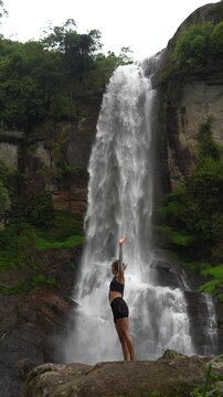 Yong lady stays on background of Ramboda waterfall in Sri Lanka.