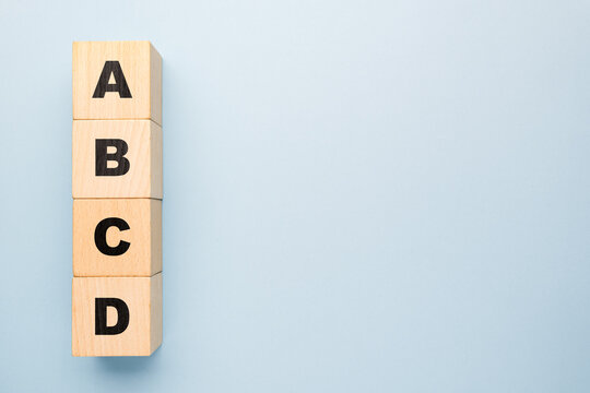 Wooden blocks stacked vertically with letters A B C D on light blue background