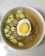 Authentic Pyongyang naengmyeon with chewy buckwheat noodles in cold, clear broth, offering a refreshing and delicate flavor. Perfect for traditional Korean cuisine menus and summer dishes.