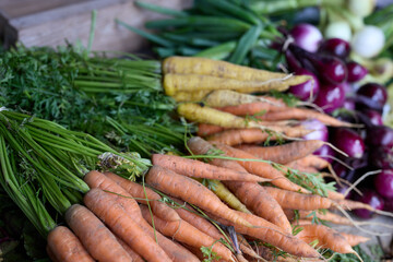 A table filled with fresh vegetables on display, like carrots onions and beetroots