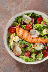 Grilled salmon fillet salad in bright overhead composition with rustic plating and fresh vegetables