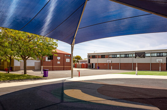 Shaded outdoor play area and sports ground with a sun sail at a public primary school campus in Australia. Concept of educational infrastructure, student recreation, and sun safety.