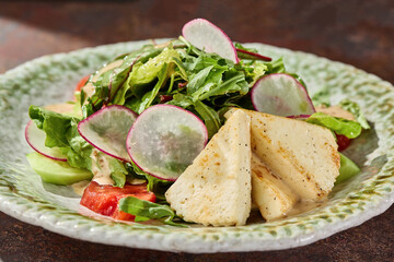 Halloumi cheese salad in bright rustic lighting, closeup composition on a ceramic plate