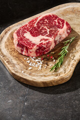 Ribeye steak with marbling, rustic lighting, overhead composition on a wooden board