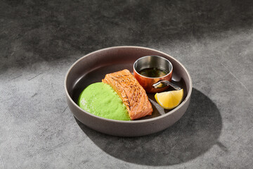 Grilled salmon steak with wasabi puree in bright rustic lighting, overhead minimal composition