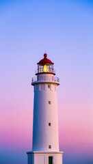 Tall white lighthouse with red cap against a colorful twilight sky