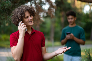 Teens with phones in hands spending time together in the park