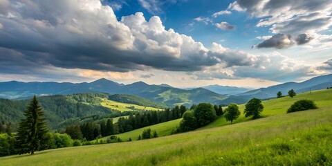 Mountain landscape with snow-capped peaks, green valleys, and clouds against a bright summer sky
