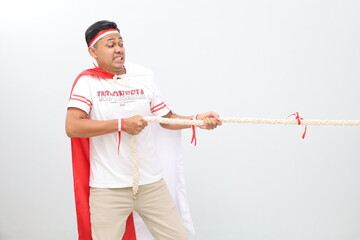 Indonesian man celebrating Indonesian independence shouting enthusiastically while pulling a rope...
