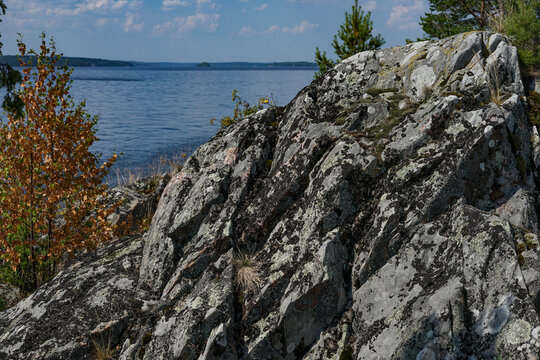 Rocky outcrop with a view of the lake and trees under a blue sky