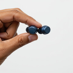 Hand Holding Wireless Earbuds, Close-Up On White Background