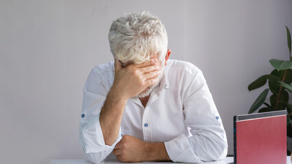 The sad businessman closes his face with his hand. Sad and thinking.