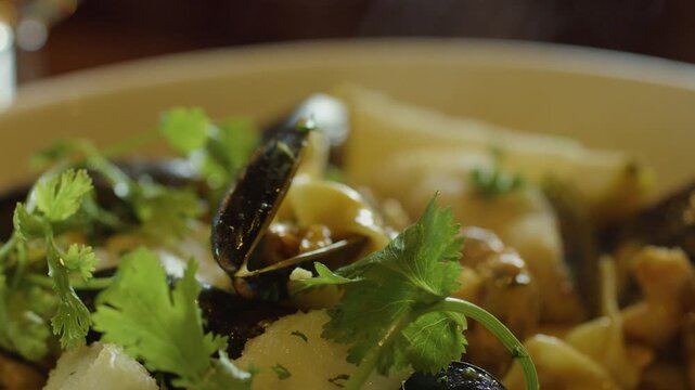 Hand Scooping Steaming Seafood Chowder With Fresh Herbs
