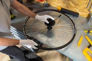 Unrecognizable male technician holding mountain bike wheel fixing tire in repair shop