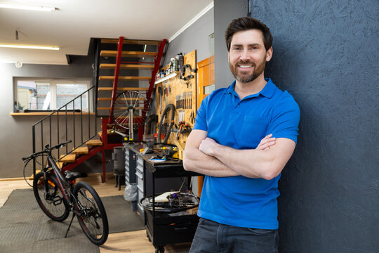 Confident bicycle mechanic standing with arms crossed in bike workshop