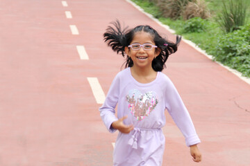5-year-old Latina brunette girl with glasses plays on public playground equipment alone as therapy for ADHD
