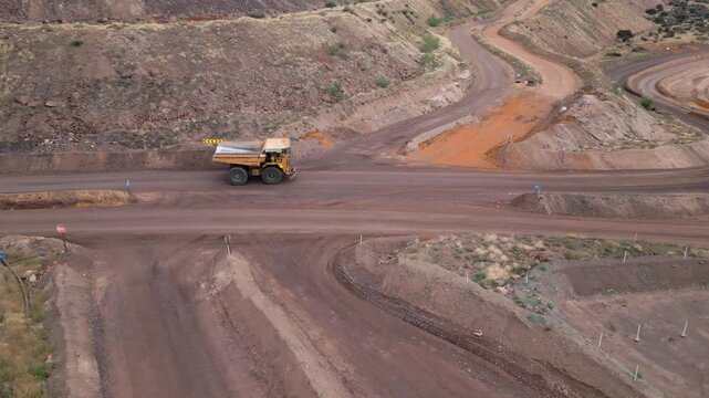 Aerial of a large tipper truck driving on a pit mine