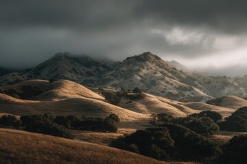 Golden hills, rugged mountains under a dramatic sky