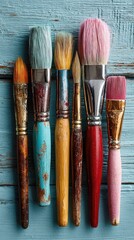 Fototapeta premium Colorful paintbrushes on weathered teal wood