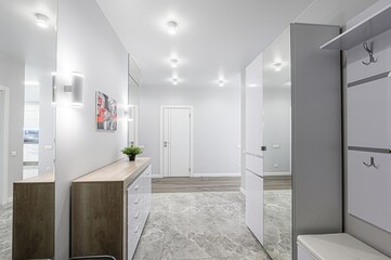 modern hallway with gray marble flooring, mirrored walls, and white and wood furniture. It features recessed lighting and minimalist decor