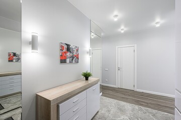 bright entryway with gray walls, white trim, light wood console, and a mirror. The floor is tiled with a marble-like pattern. A modern, clean design