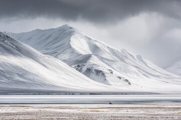 Snowy mountain range meets a frozen lake under a dramatic sky