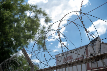 Barbed Wire Fences Enclosing a Restricted Area on a Bright Day With Blue Skies and Fluffy Clouds Above