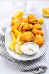 Traditional fish and chips with lemon and tartar sauce on serving plate
